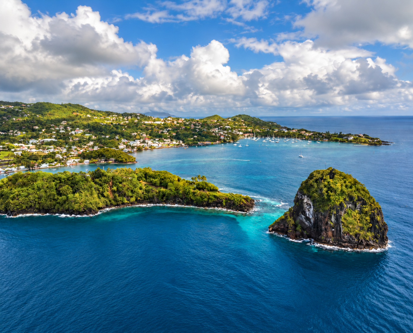 Aerial view of the St Vincent coastline with a forested islet, turquoise bays and boats anchored near Calliaqua