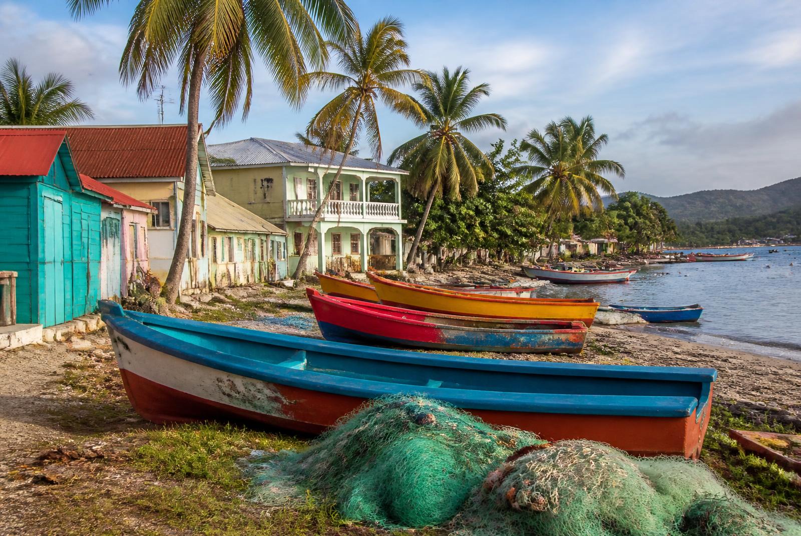 Brightly painted wooden fishing boats on the shore of a Caribbean village