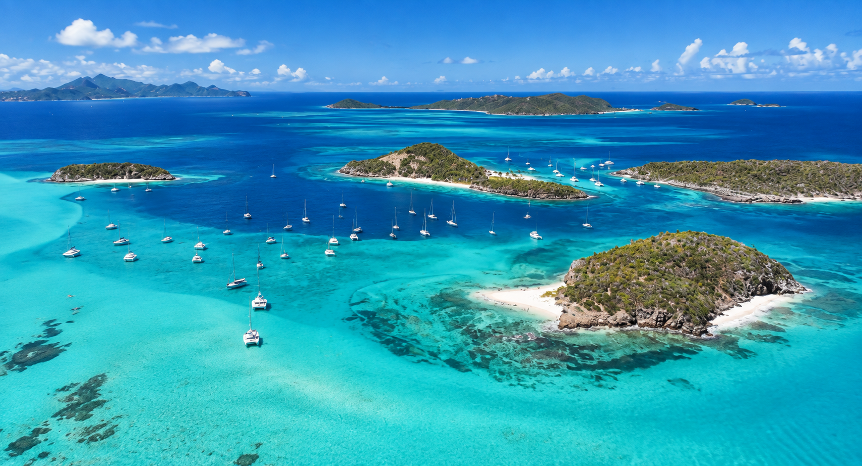 Aerial view of the Grenadines with sailboats anchored among small islands, white sand beaches and turquoise water