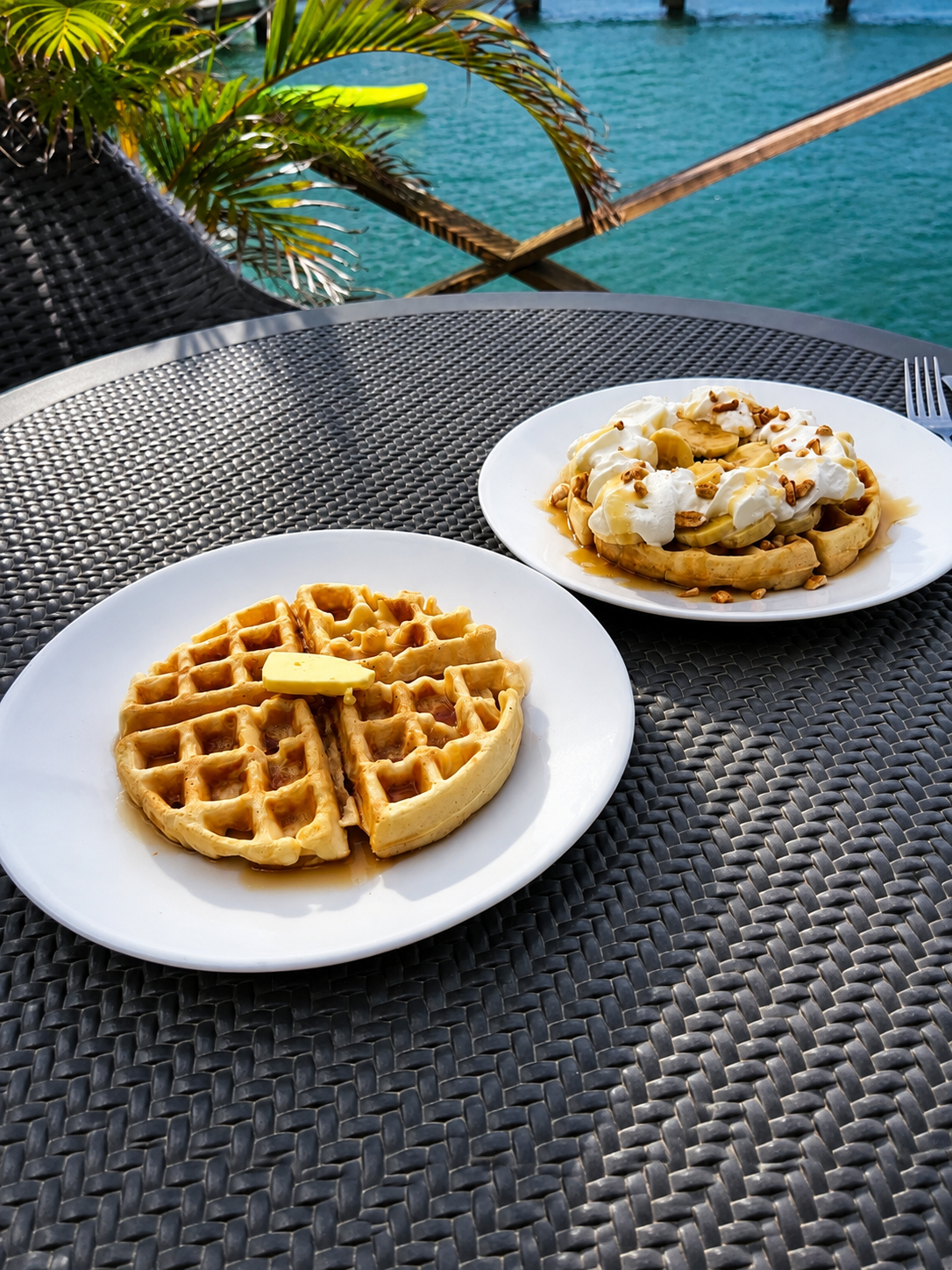 Waffles and fresh tropical fruit on a table on the waterfront deck at Point Bay Resort